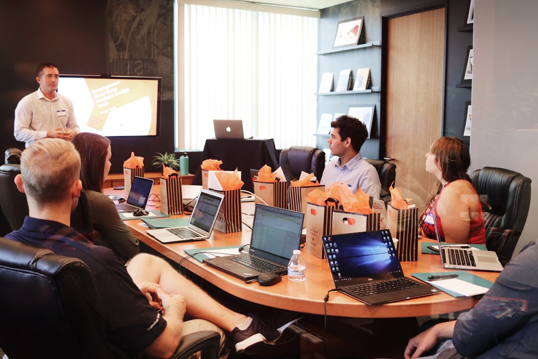 costa mesa seo — man standing in front of people sitting beside table with laptop computers